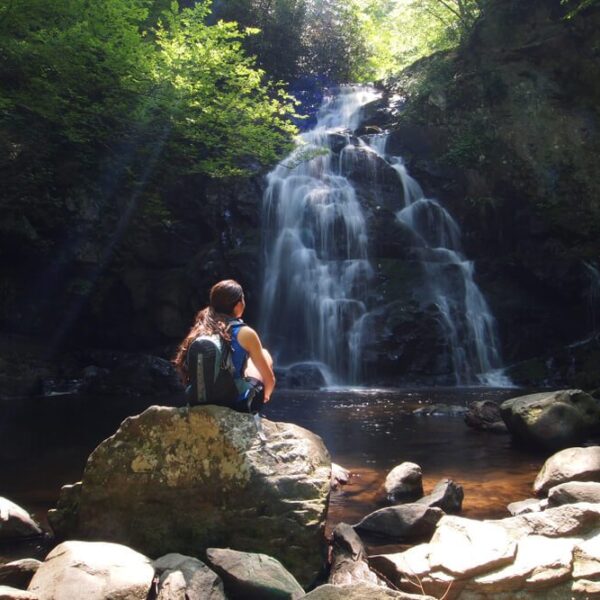 A woman hiking to a waterfall, one of the best free or inexpensive things to do in Gatlinburg.