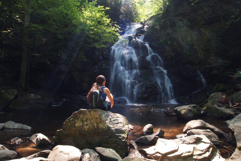 A woman hiking to a waterfall, one of the best free or inexpensive things to do in Gatlinburg.