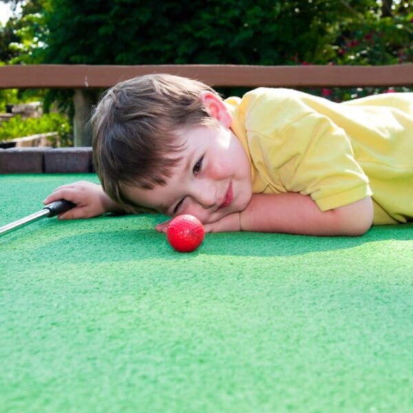 A kid playing mini golf at at Gatlinburg course.